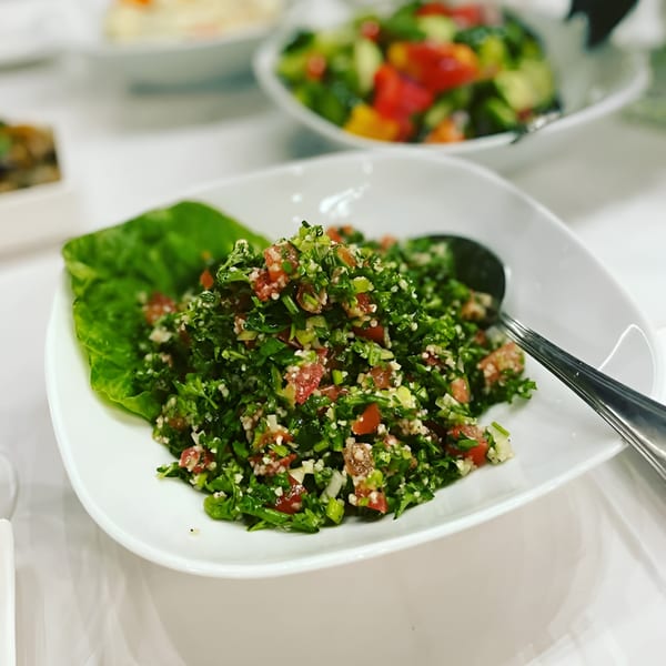 Close-up of a fresh tabbouleh salad with parsley, tomatoes, and bulgur in a white bowl.