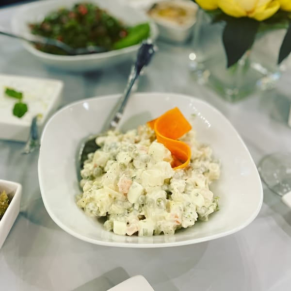Creamy potato salad with peas and carrots, garnished with an orange carrot curl, at Asteria Restaurant.